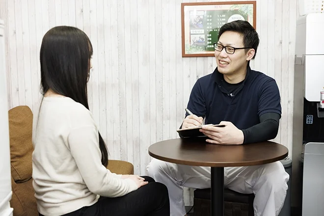 テーブルを挟んで来店者の話を聞くスタッフ